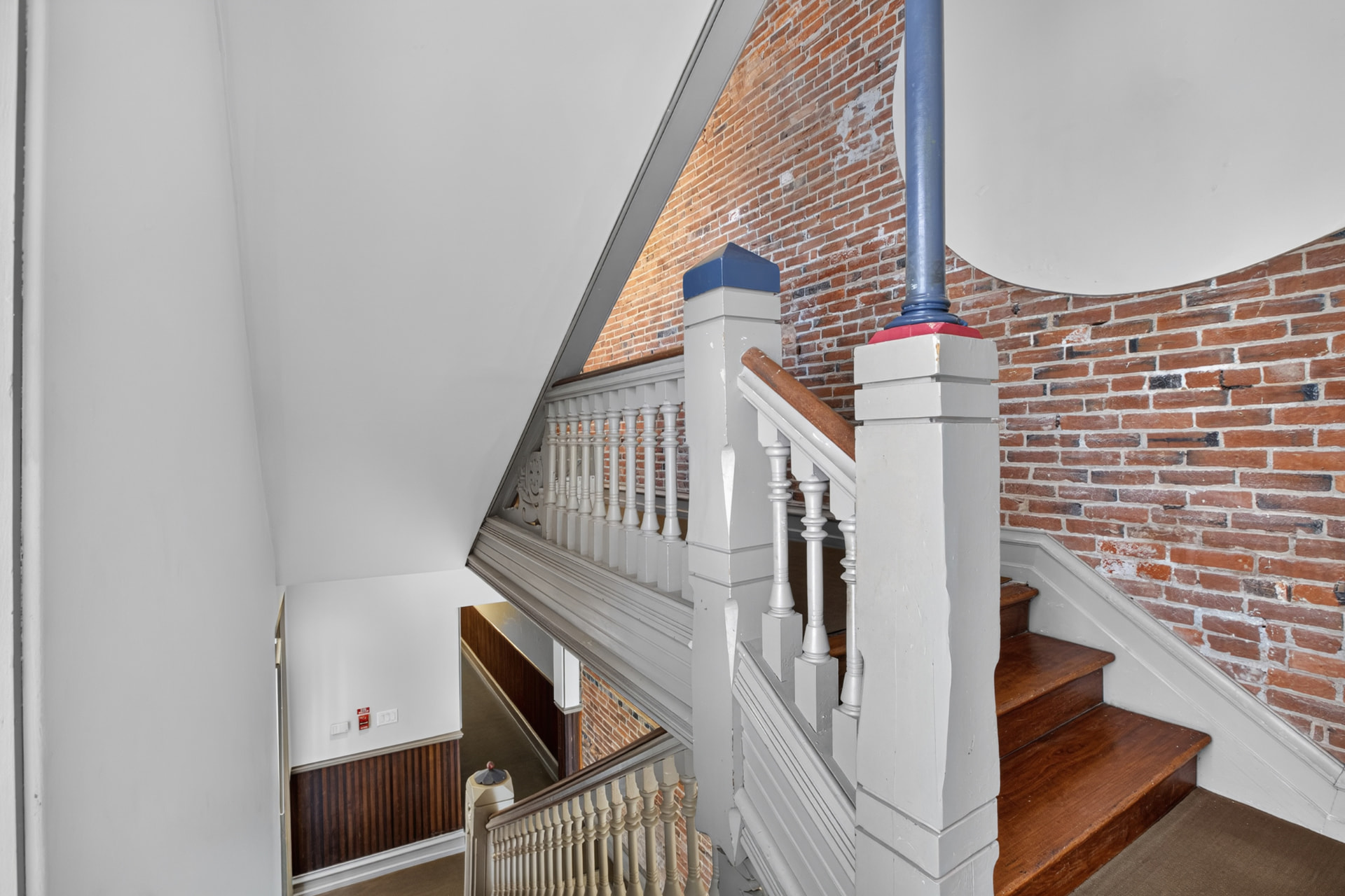 Original turned balustrade stair rising against exposed brick