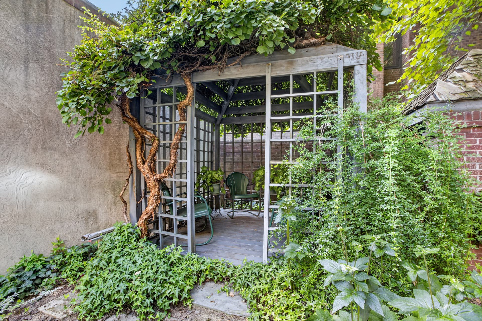 Vine covered garden pavilion with trellis and period metal seating