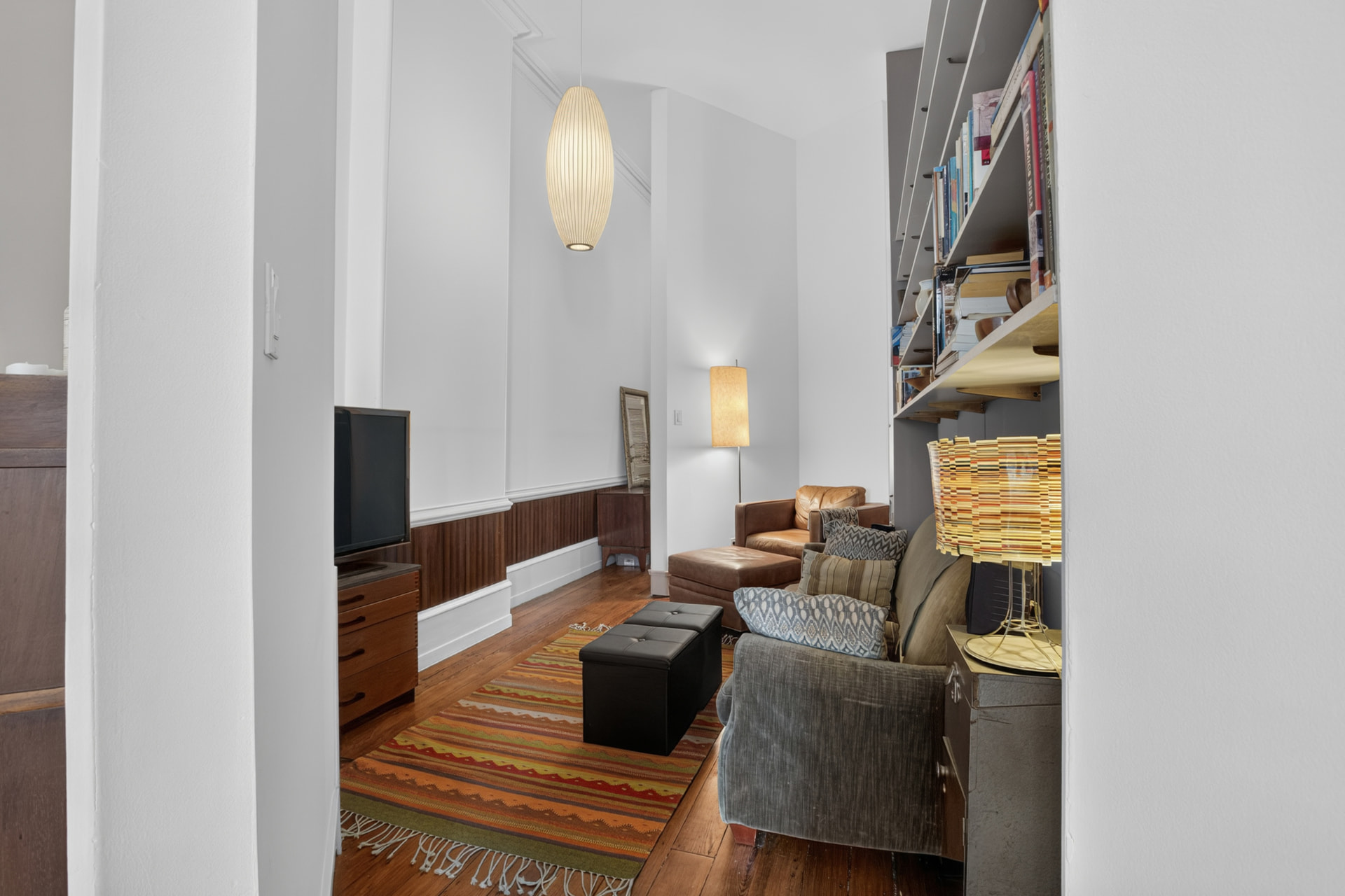 High ceilinged sitting room with wood wainscoting and built in bookshelves